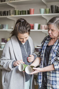 Female potters examining at coffee cups in ceramics workshop