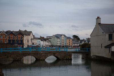 Bridge over river by buildings against sky in city