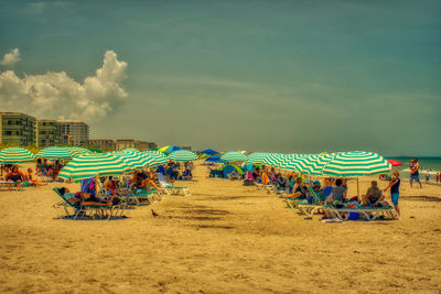 People enjoying beach against sky