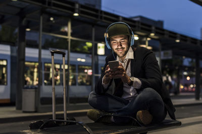 Young man in the city with headphones and cell phone in the evening