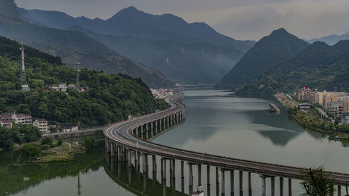 High angle view of bridge over river amidst mountains against sky