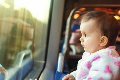 Cute baby girl looking though window in train
