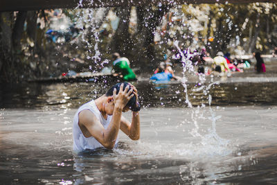 Man with head in hands amidst splashing water in lake