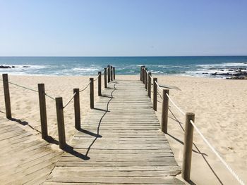 Wooden posts on beach against clear sky