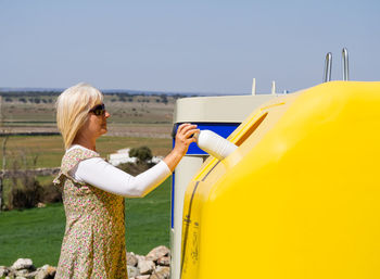 Woman holding yellow umbrella against clear sky