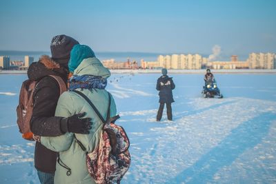 Rear view of women walking on snow during winter