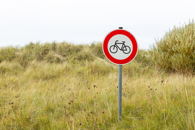 Road sign on field against sky