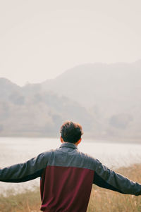 Rear view of man standing on mountain against sky