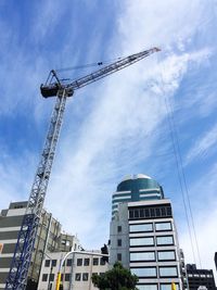 Low angle view of crane against cloudy sky