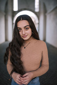 Confident teenage girl with long hair standing on footpath in tunnel