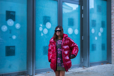 Portrait of young woman standing against red wall