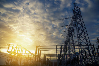 Low angle view of silhouette electricity pylon against sky