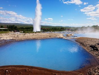 Smoke emitting from volcanic landscape against blue sky