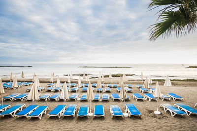 Lounge chairs on beach against sky