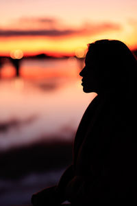 Side view of young man looking away at beach during sunset