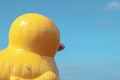Low angle view of yellow sculpture against blue sky