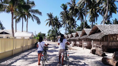 Rear view of man and women with bicycles at tourist resort