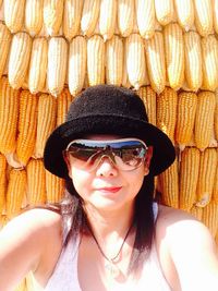 Portrait of smiling young woman wearing sunglasses against corns