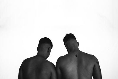 Rear view of shirtless men against white background