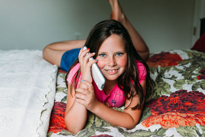 Portrait of happy girl lying on bed at home