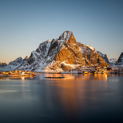 Scenic view of lake by snowcapped mountain against clear sky