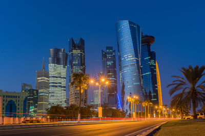 Illuminated buildings against clear blue sky at night