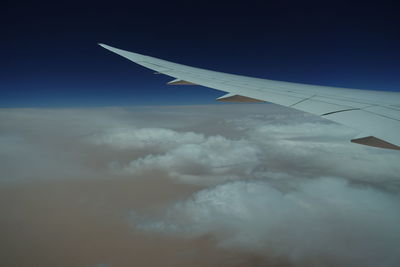 Airplane wing flying over clouds in sky