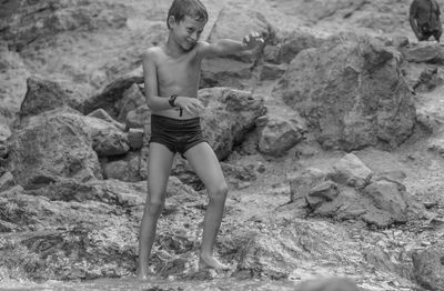 Full length of shirtless young woman on beach