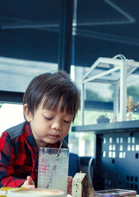 Cute boy drinking juice on table in restaurant