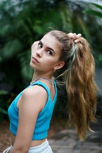 Portrait of young woman standing against trees