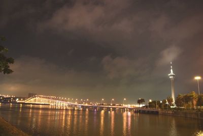 Illuminated bridge over river against sky in city at night