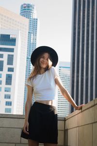 Portrait young woman in a hat standing against building