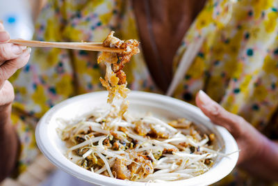 Close-up of hand holding noodles in bowl