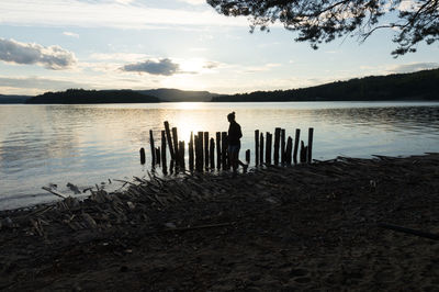 Scenic view of wooden posts in lake against sky