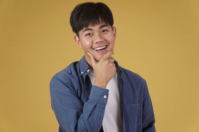 Portrait of a smiling young man against yellow background