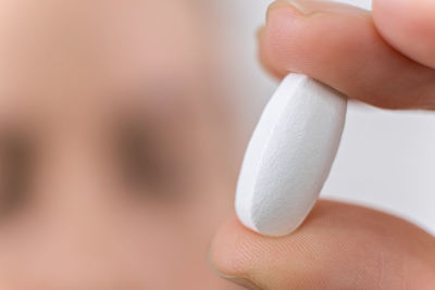 Macro photo of hand holding white pill. medical capsule, supplement or antibiotic, pharmaceutical 