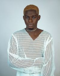 Portrait of young man standing against wall