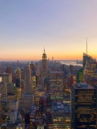 Illuminated cityscape against sky during sunset