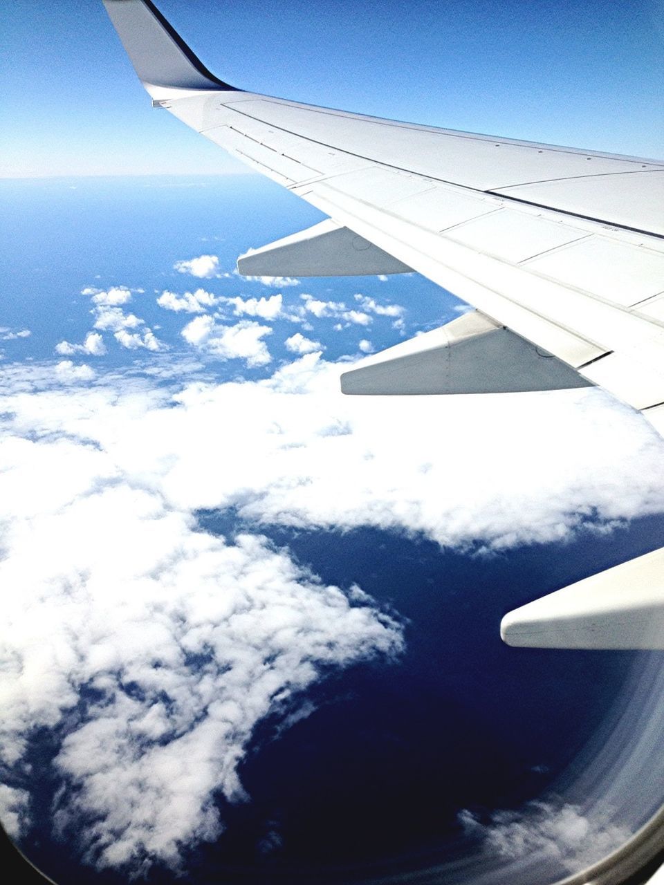 airplane, aircraft wing, air vehicle, flying, transportation, mode of transport, aerial view, part of, cropped, mid-air, sky, travel, journey, on the move, airplane wing, landscape, public transportation, scenics, vehicle part, blue