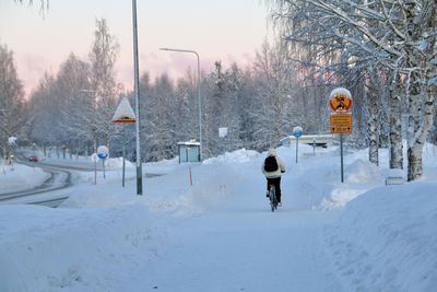 Rear view of man walking on snow covered field