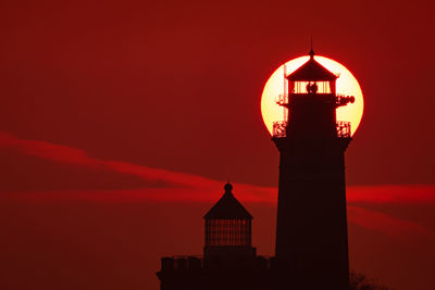 Silhouette of lighthouse against orange sky