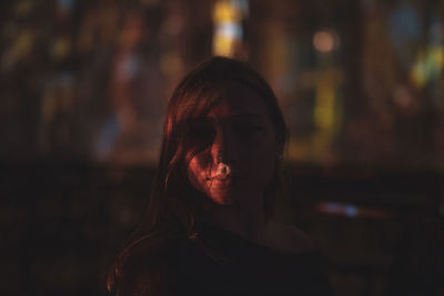 Close-up portrait of young woman standing outdoors at night