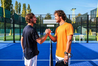 Happy men standing at tennis court