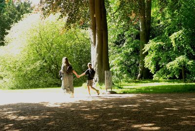 Woman walking by plants against trees