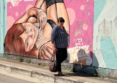 Woman standing by graffiti on wall
