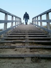 Low angle view of man walking up stairs against clear sky