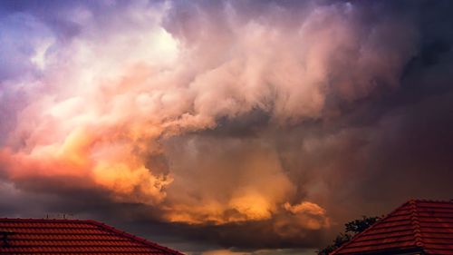 Low angle view of house roof against sky during sunset