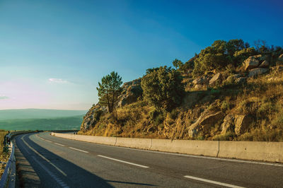 Country road passing on hilly landscape with rocks at the highlands of serra da estrela. portugal.