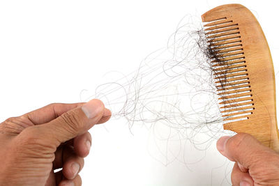 Close-up of hand holding paper over white background