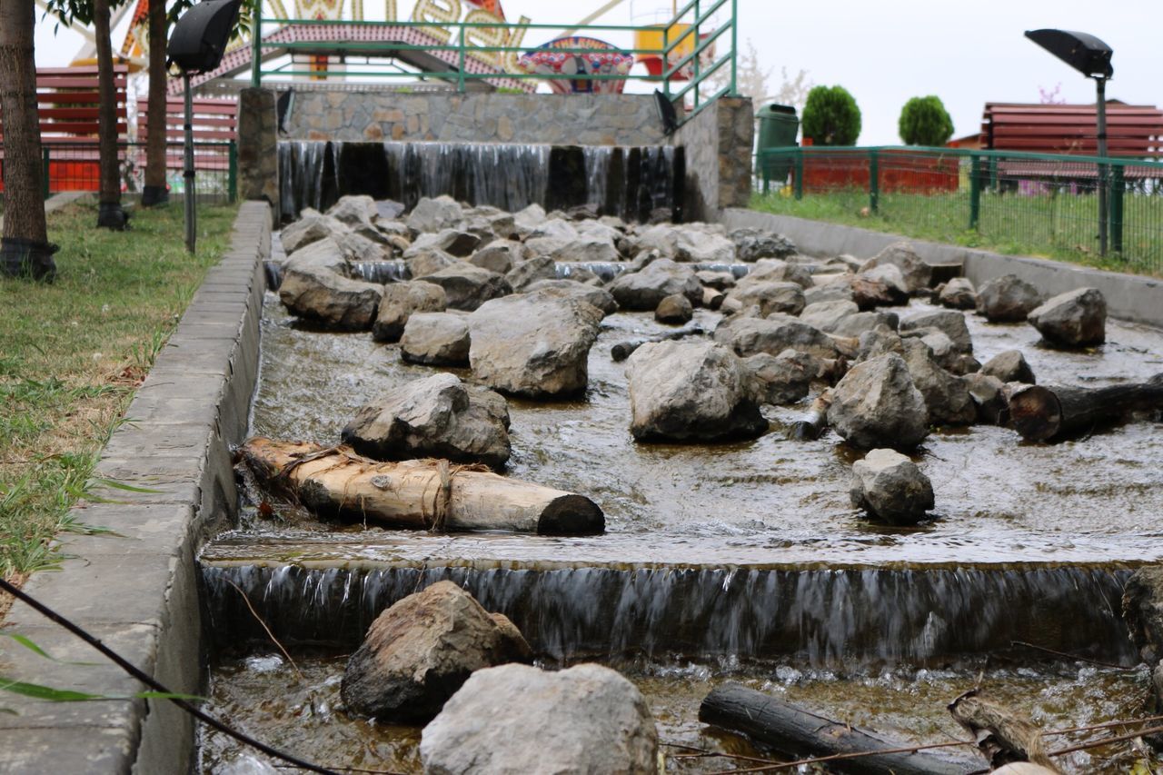 animal themes, built structure, wood - material, architecture, fence, building exterior, domestic animals, day, outdoors, stone wall, rock - object, house, log, firewood, stone - object, livestock, no people, stack, mammal